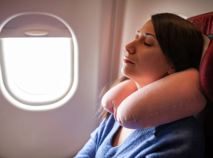 ragazza che dorme in aereo con cuscino da viaggio